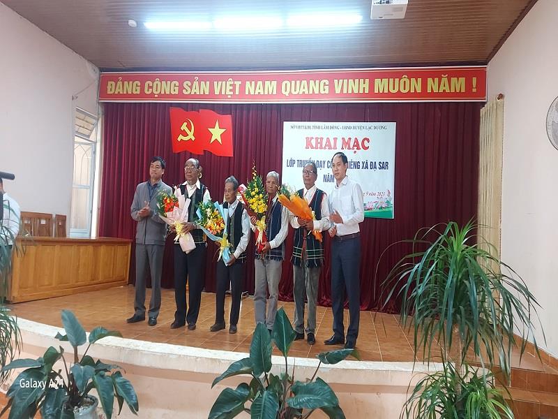 Đồng chí Trần Tuấn Anh - Bí thư Đảng ủy xã Đạ Sar (trái ảnh) và đồng chí Nguyễn Vũ Hoàng - Trưởng phòng Văn hóa và Thông tin tặng hoa cảm ơn các nghệ nhân tham gia truyền dạy