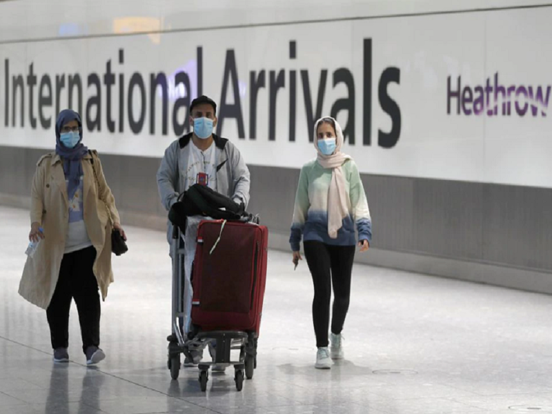 Khách du lịch đeo khẩu trang khi di chuyển tại sân bay Heathrow, Anh. Ảnh: Reuters