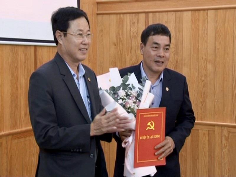 Bí thư Huyện ủy Phạm Triều (trái ảnh) trao quyết định và tặng hoa chúc mừng đồng chí Nguyễn Văn Huynh