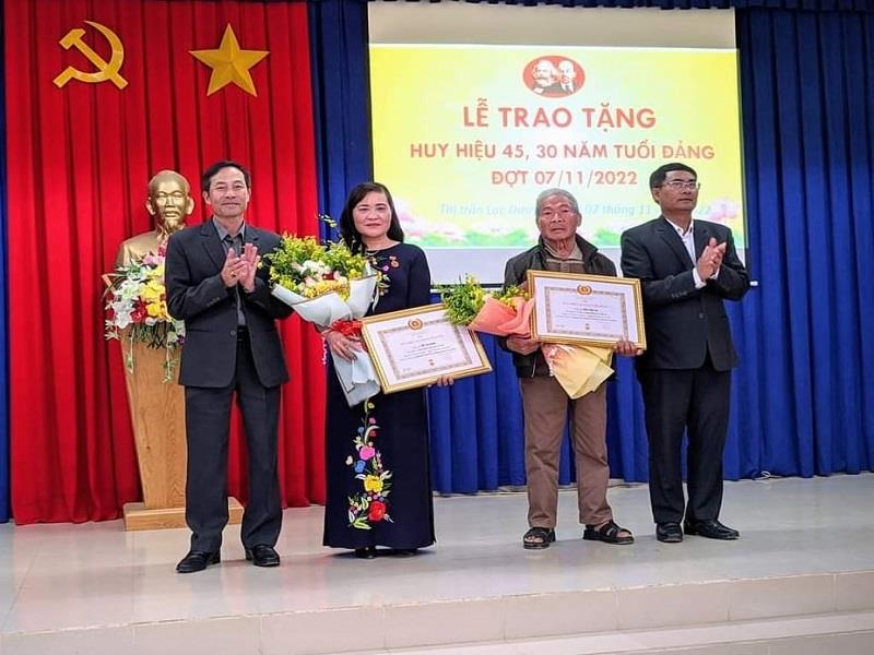 Đồng chí Ya Tiong - Phó Bí thư Thường trực Huyện ủy (phải ảnh) và đồng chí Nguyễn Văn Thụy - Bí thư Đảng ủy thị trấn trao Huy hiệu Đảng cho 02 đảng viên của thị trấn