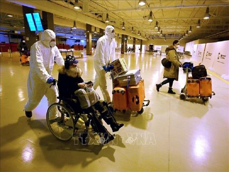Nhân viên y tế hỗ trợ hành khách đến từ Trung Quốc sau khi xét nghiệm COVID-19 tại sân bay quốc tế  Rome - Fiumicino ở Italy (ảnh: AFP/TTXVN)